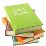 Diet book A green hardcover book titled "Diet Book," exploring what is dieting, rests atop a stack of colorful hardcover books against a white background.